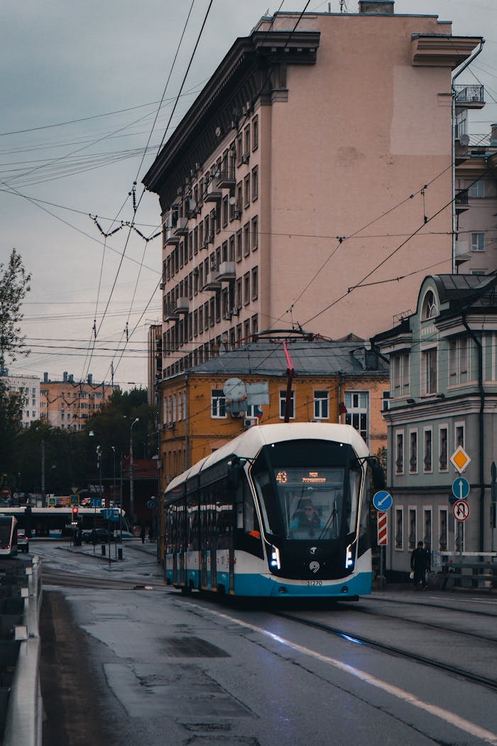hero-img-01 A sleek, modern tram travels down a wet street in Moscow, Russia during the early hours.